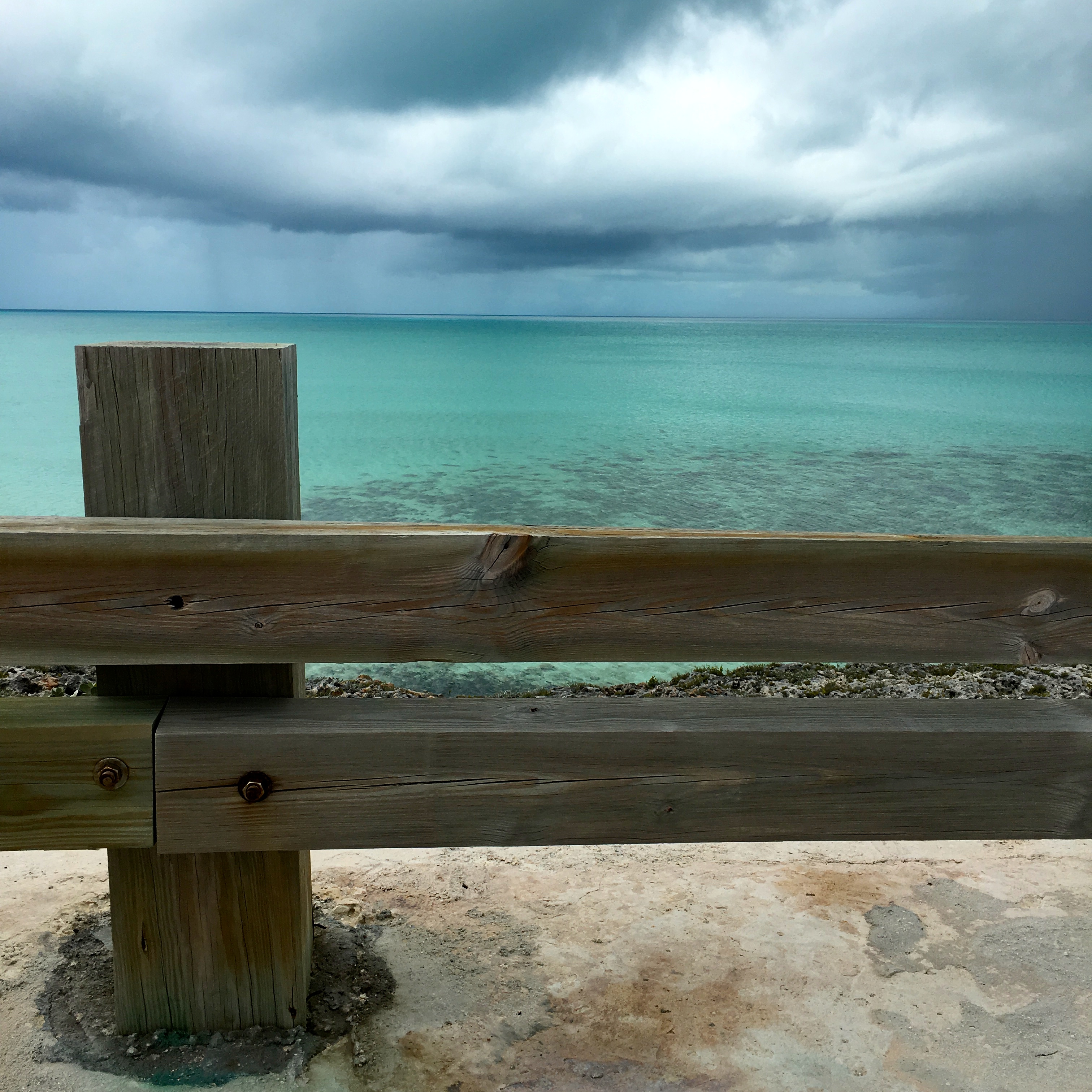 brown wooden fence near body of water under cloudy sky at daytime
